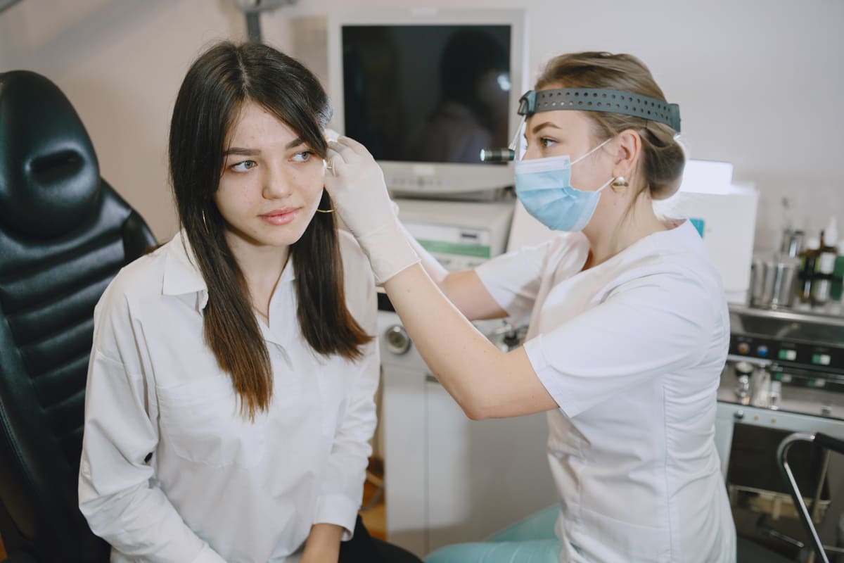 woman patient medical office doctor checks woman ears